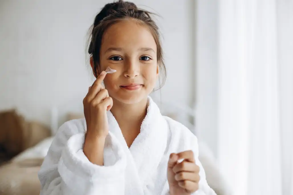 Seorang anak perempuan sedang menggunakan moisturizer di wajahnya. Source: Petro Seniv 888/Freepik